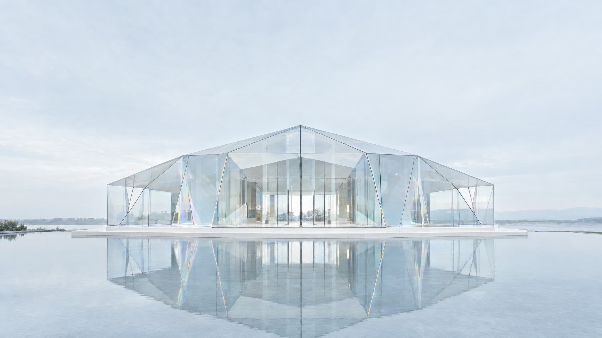 A glass pavilion standing on calm water